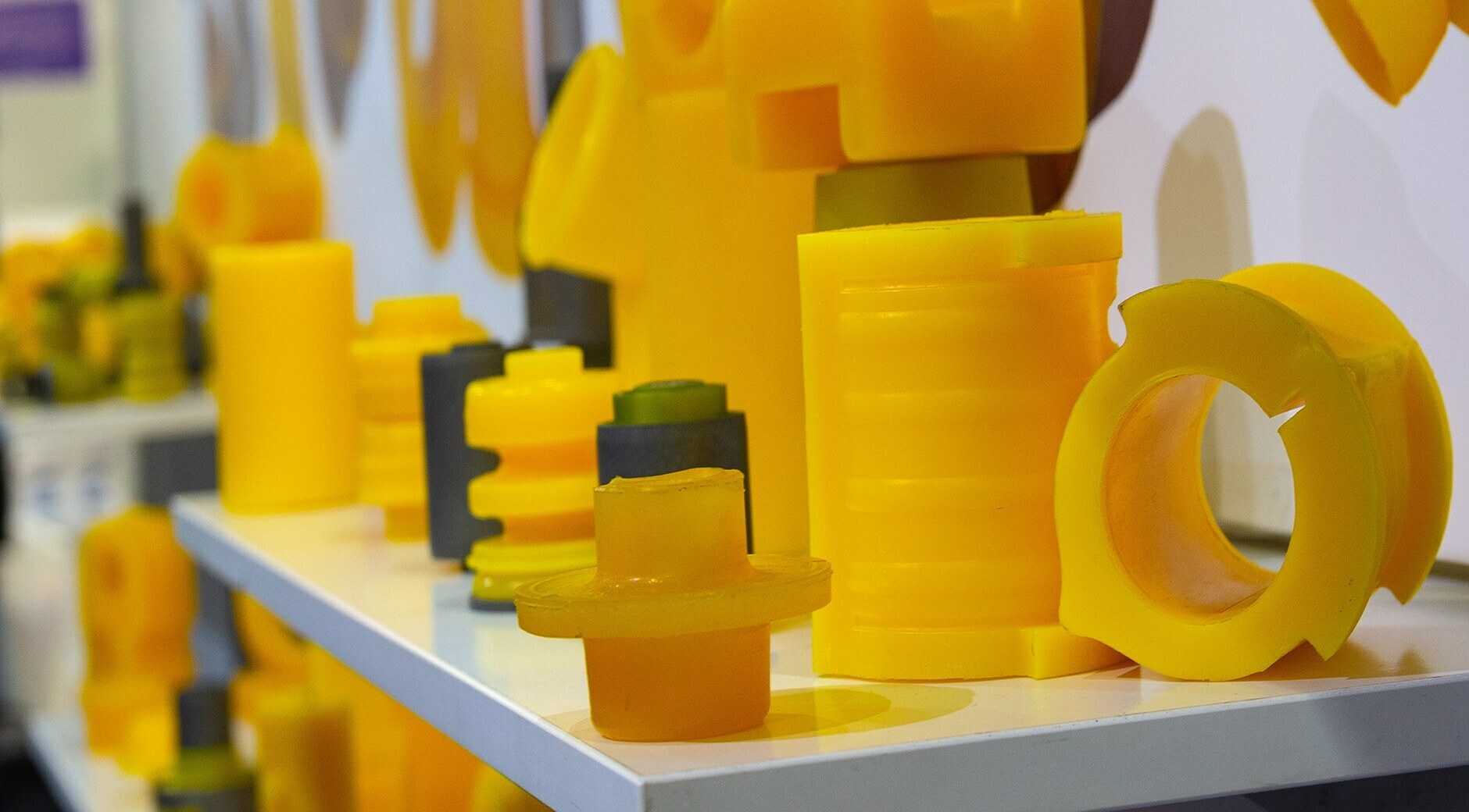 Molded yellow polyurethane parts and bushings lined up on workshop table